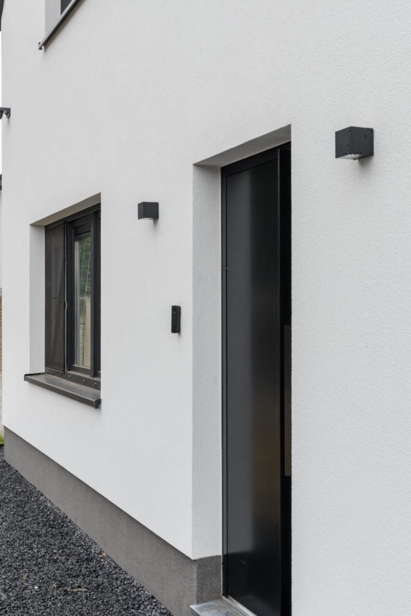 Witte siliconenpleister en antraciet plint aan de gevel in Zonhoven