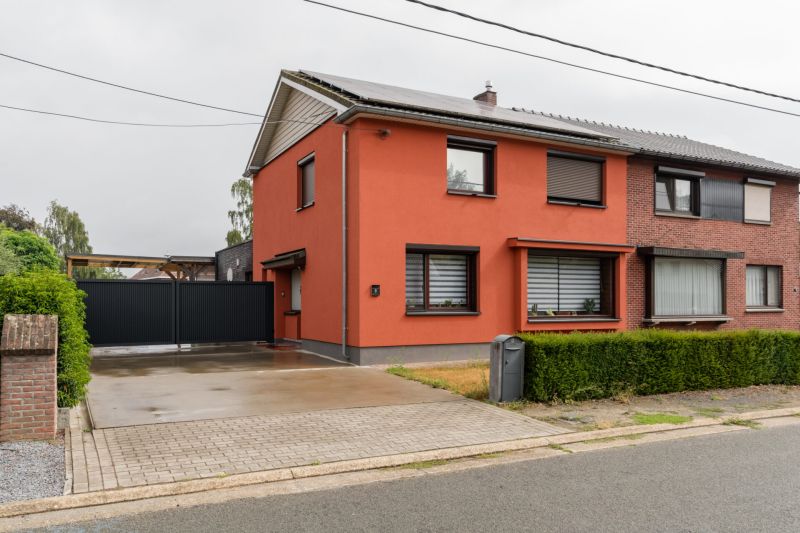 Straatzicht van de gerenoveerde woning met rood-oranje gevel in Houthalen